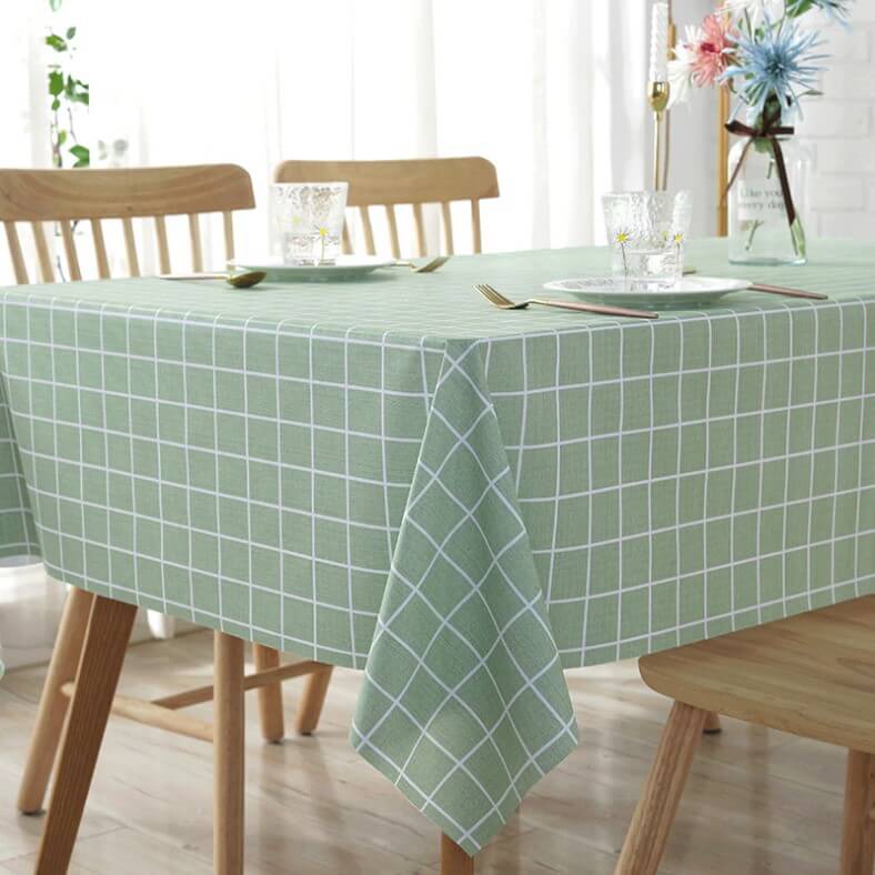 A tablecloth with 2 dinner sets over a wooden table and chair set.